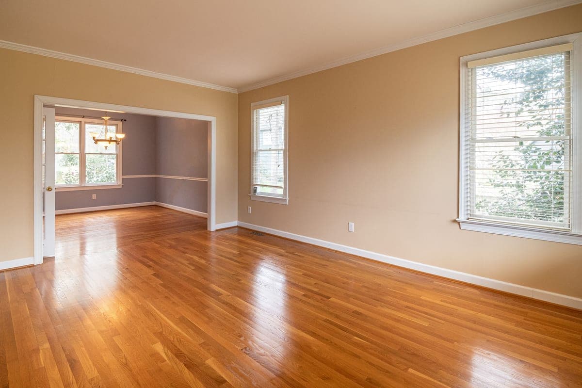 A bright empty room with wooden floors and large windows
