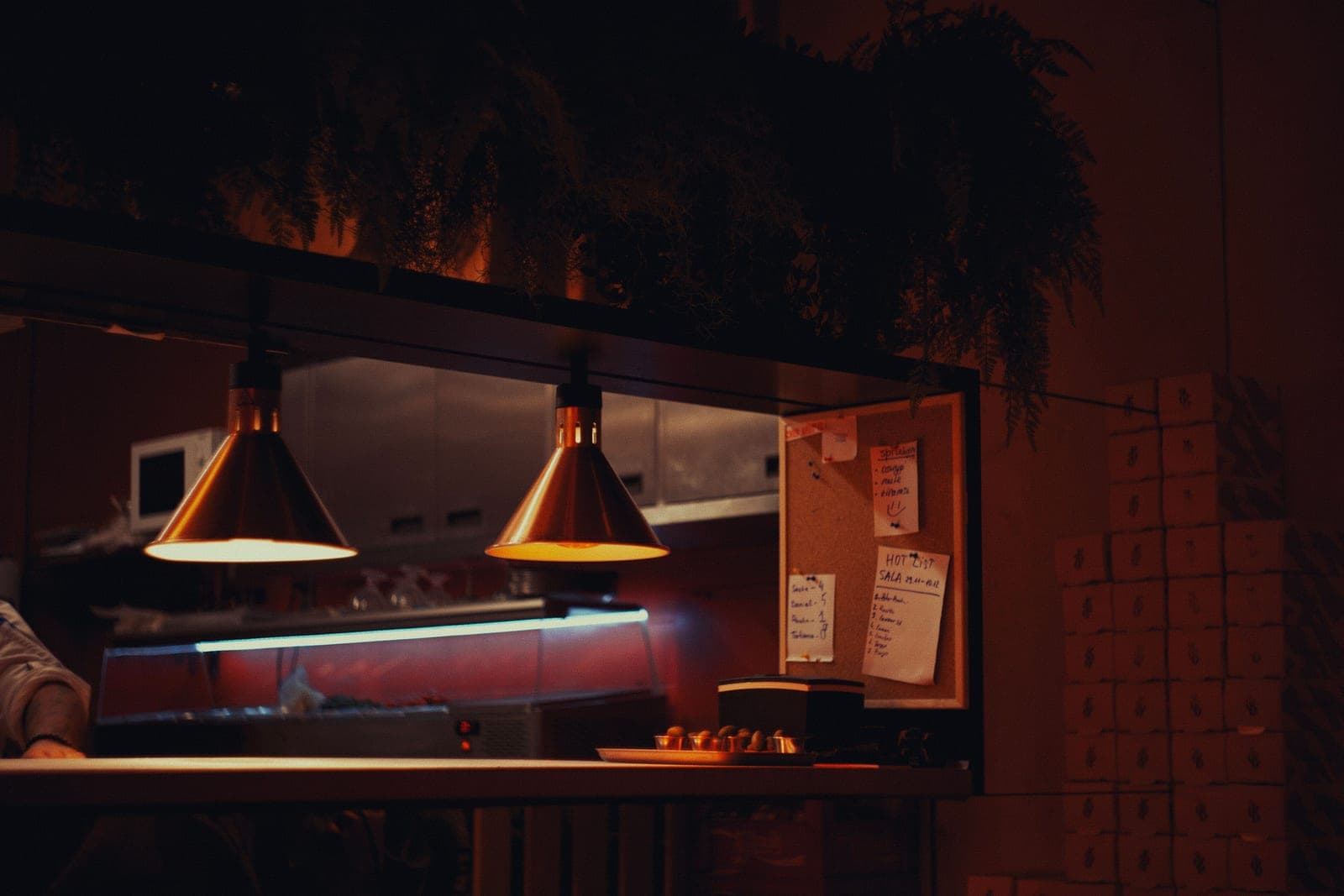 A warmly lit kitchen interior with a counter and lamps at night