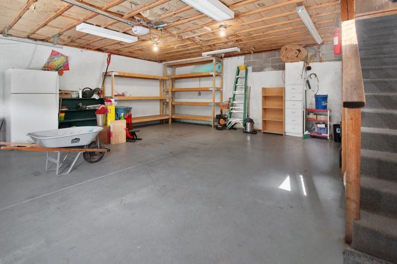 A garage interior with storage shelves and tools along the wall
